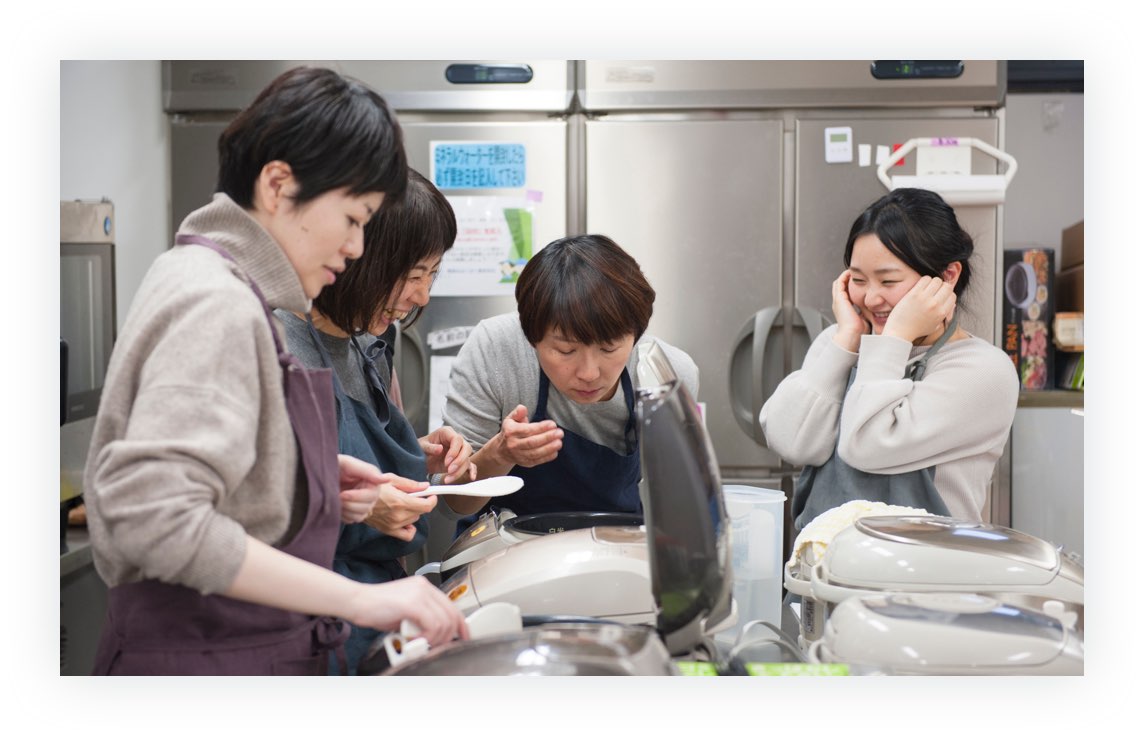 画像（8枚中7枚目）：炊飯器を並べて麦ごはんを炊いて実験しているメンバーたちの写真