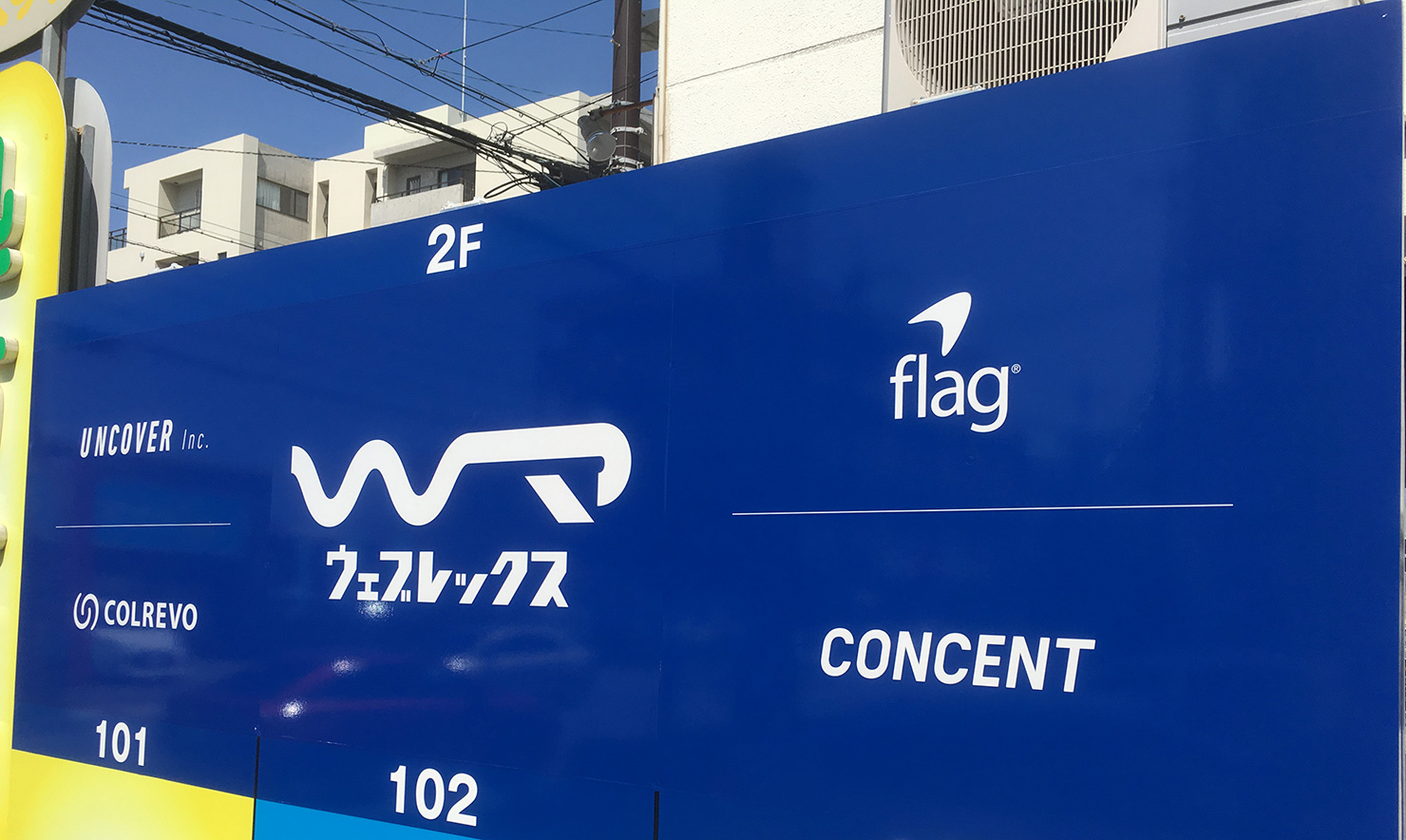 写真:ウェブレックスと4社のロゴが入った看板
