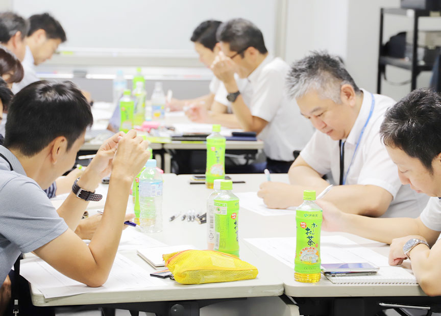 写真（5枚中3枚目）：ワークショップの様子。4人ひと組のチームになりまずは個人のアイディアを書き留める。