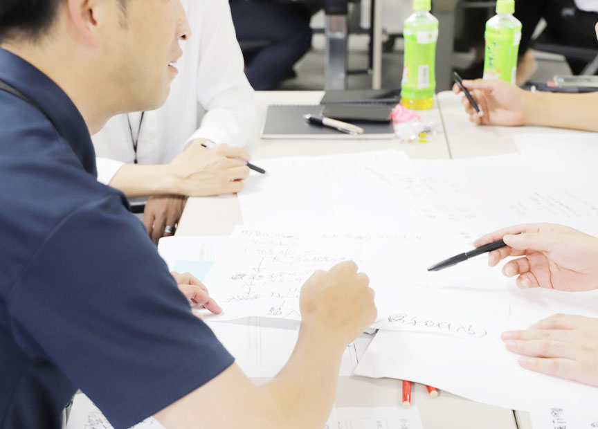 写真（5枚中4枚目）：ワークショップの様子。チーム内で擦り合わせている。