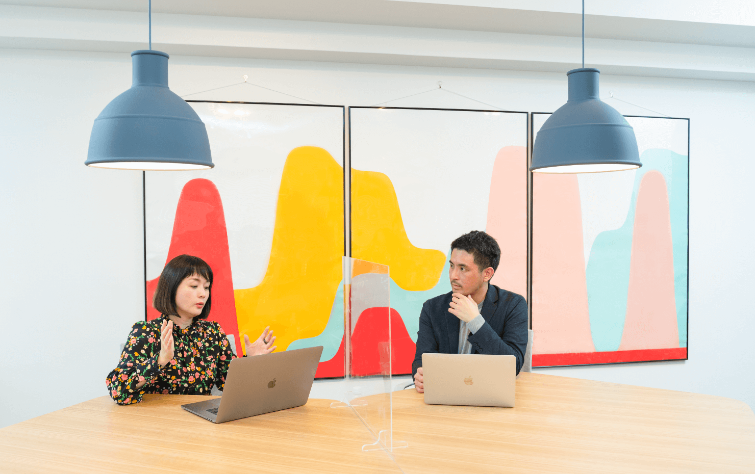 データビズラボのオフィス内、永田氏と大崎が並んで座っている。デスク上には透明なアクリル板が立てられている。