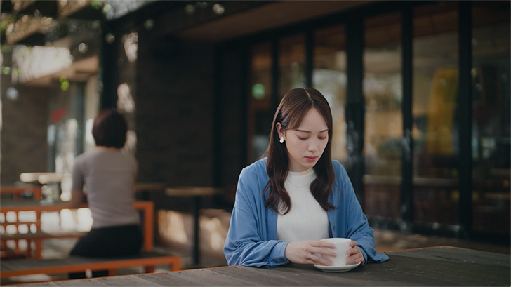 TVCMのキャプチャ:8枚中1枚目。カフェで女性がコーヒーカップを持ちながら、俯きがちに映っている。