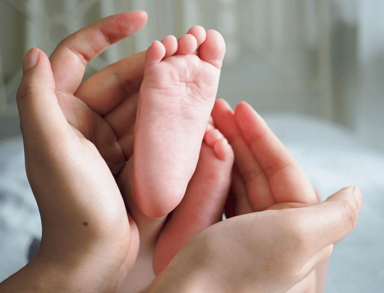 9枚中4枚目：作例写真の一部抜粋。赤ちゃんの足をママの手が包み込む様子
