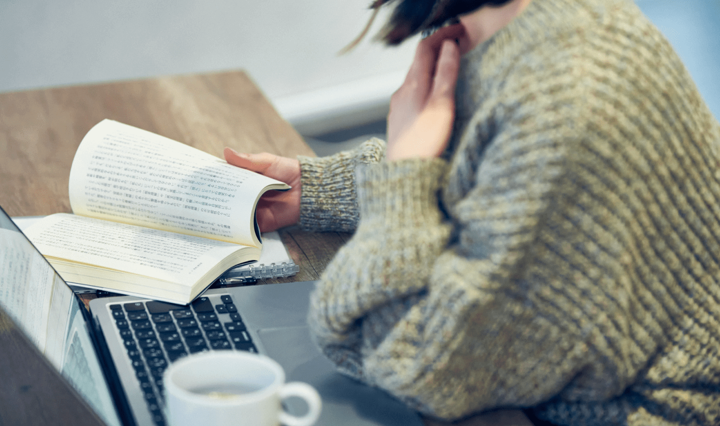 写真:坂本の手元。本を読んでいる様子。