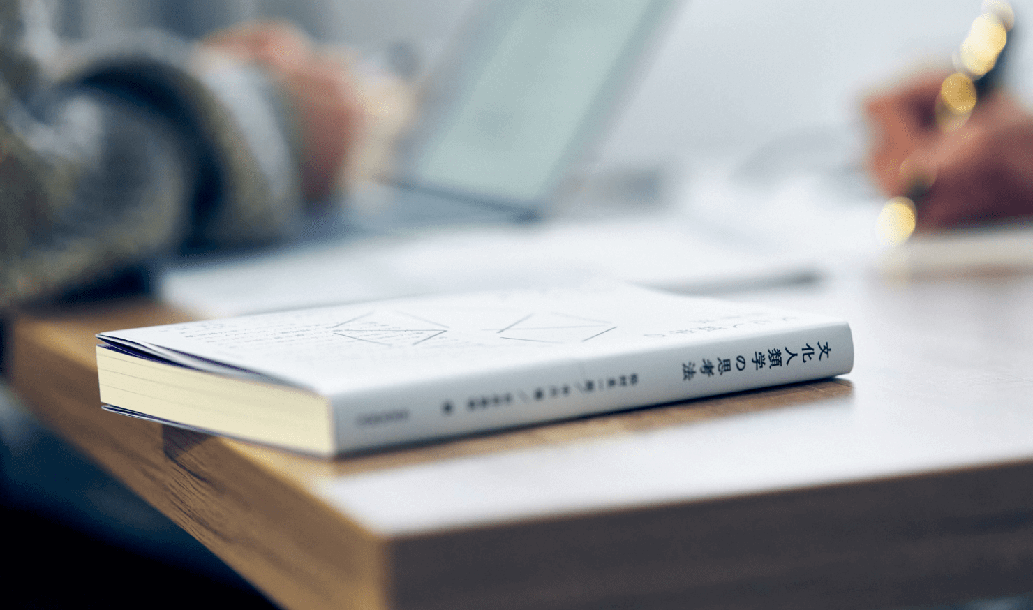 写真:書籍の写真。背景に対談する二人の手元がぼかしで映っている。