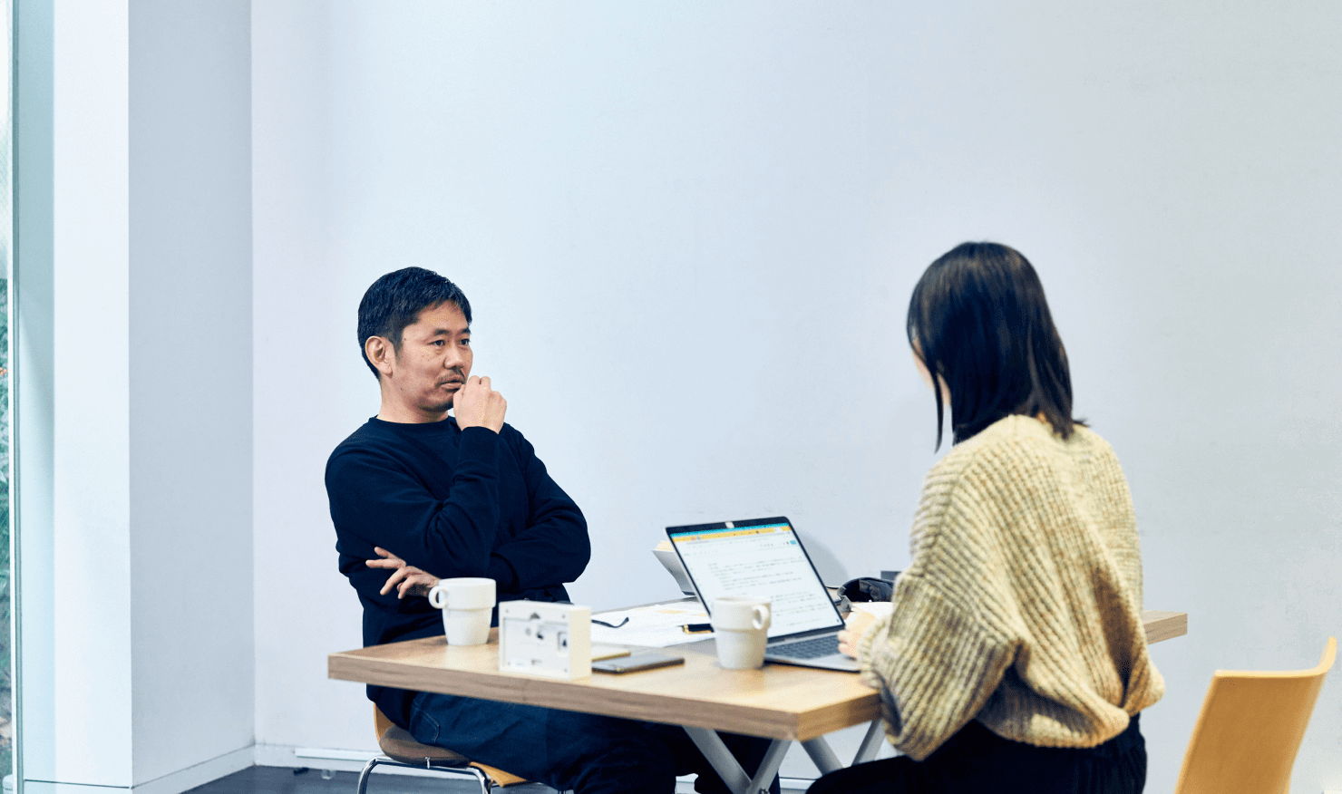 写真:長谷川・坂本が机を面して対談している様子。