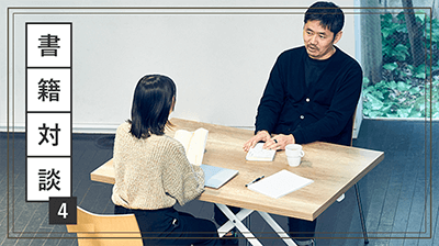 写真：坂本と長谷川が机を面して対談している様子。