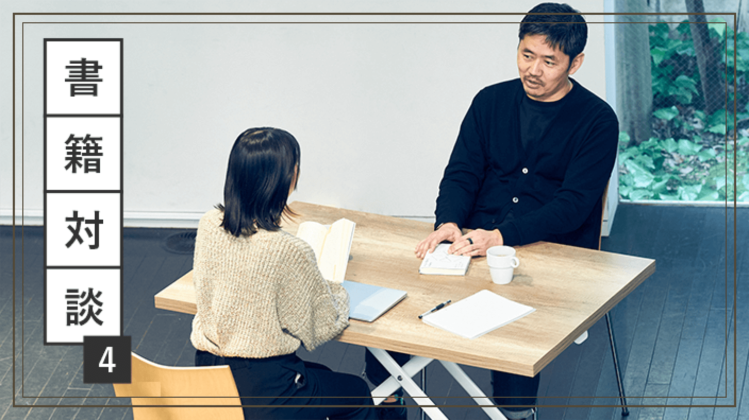写真:坂本と長谷川が机を面して対談している様子。