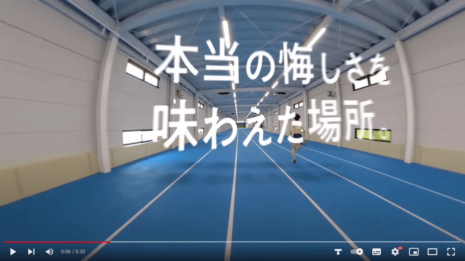 動画キャプチャ:学生が屋内トラックで、空中に浮かぶ「本当の悔しさを味わえた場所。」のコピーを走り過ぎていく様子