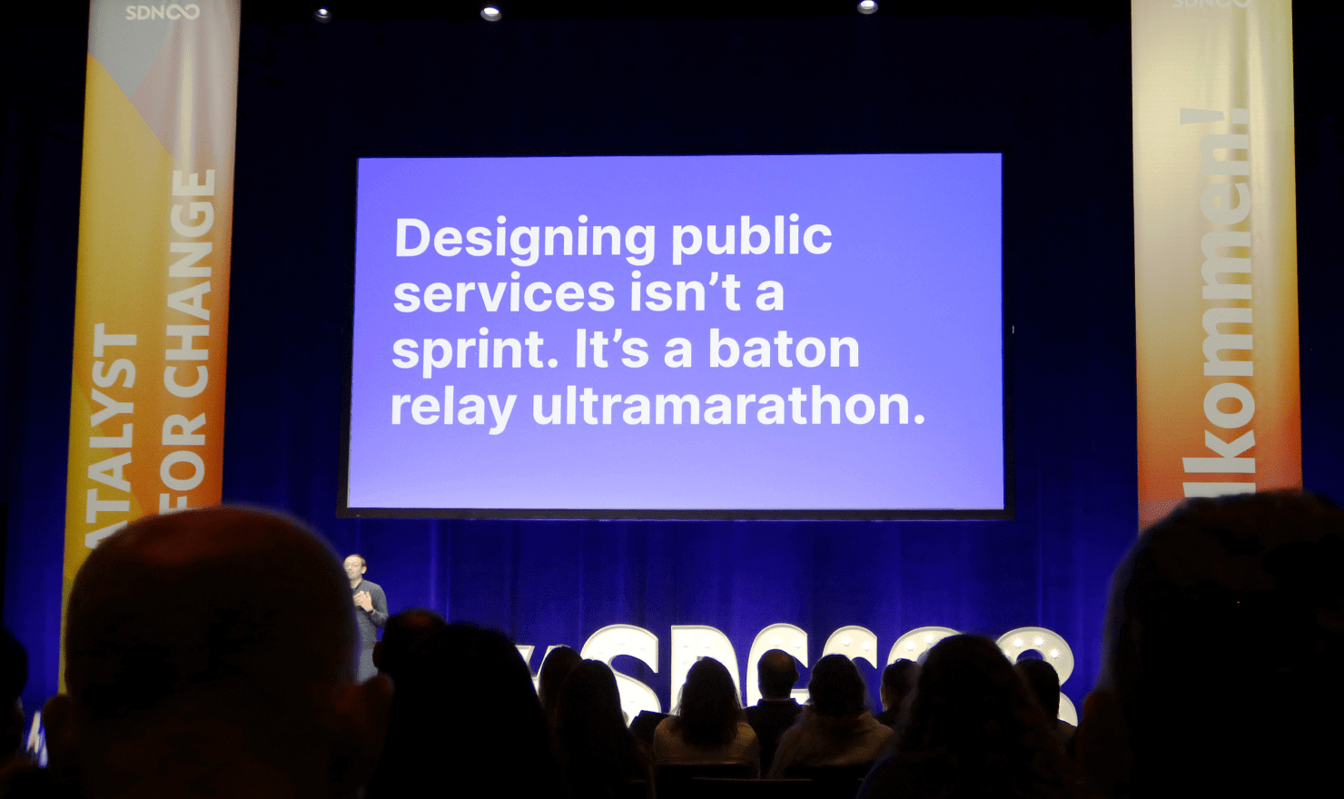 画像：Martin Jordan 氏とKara Kane 氏のトーク中のスライド “Designing public services isn’t a sprint. It’s a baton relay ultramarathon.”