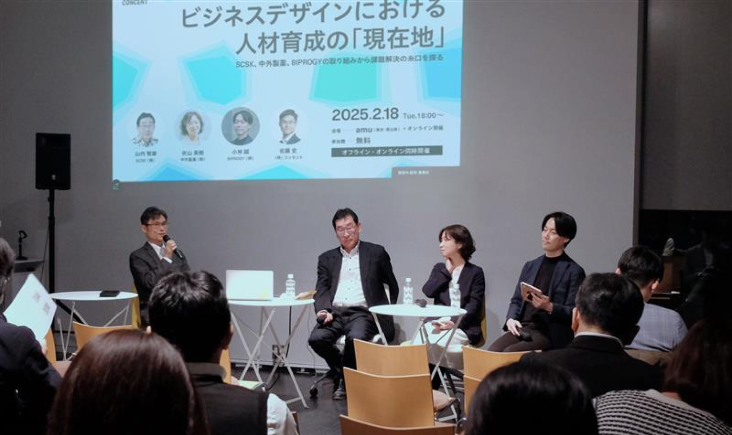 セミナーでのパネルディスカッションの様子。前方の登壇スペースに登壇者4名が椅子に着席し、話している。