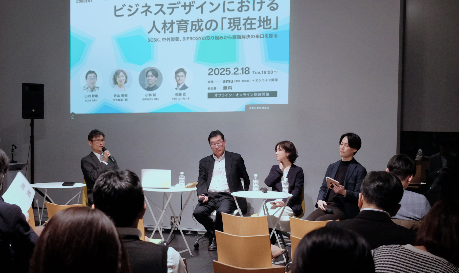 セミナーでのパネルディスカッションの様子。前方の登壇スペースに登壇者4名が椅子に着席し、話している。