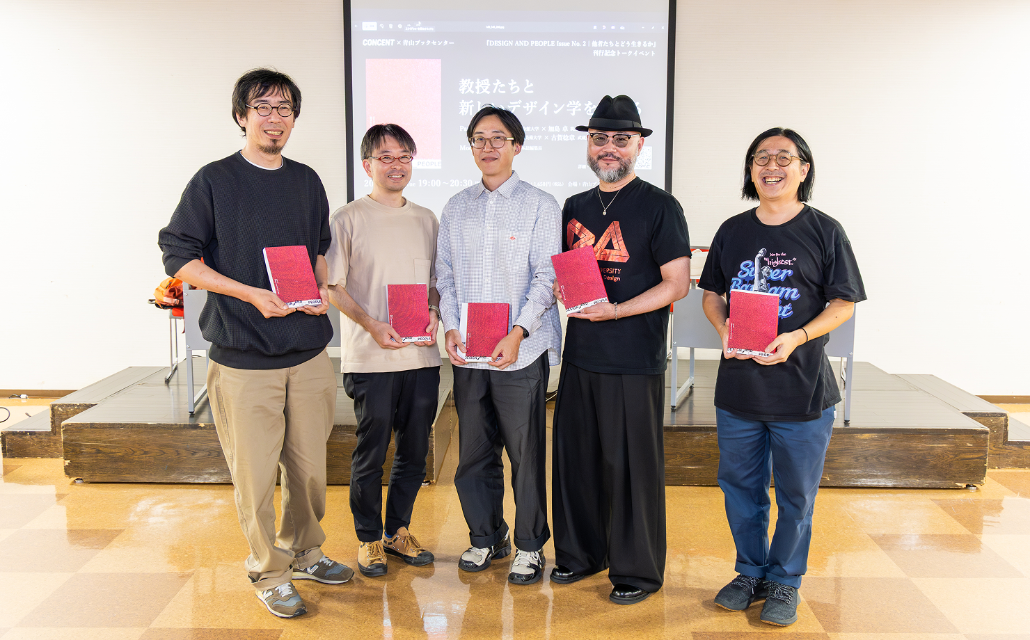 イベント会場で、パネリストとモデレーターが『DESIGN AND PEOPLE Issue No.2』を手に並んでいる様子