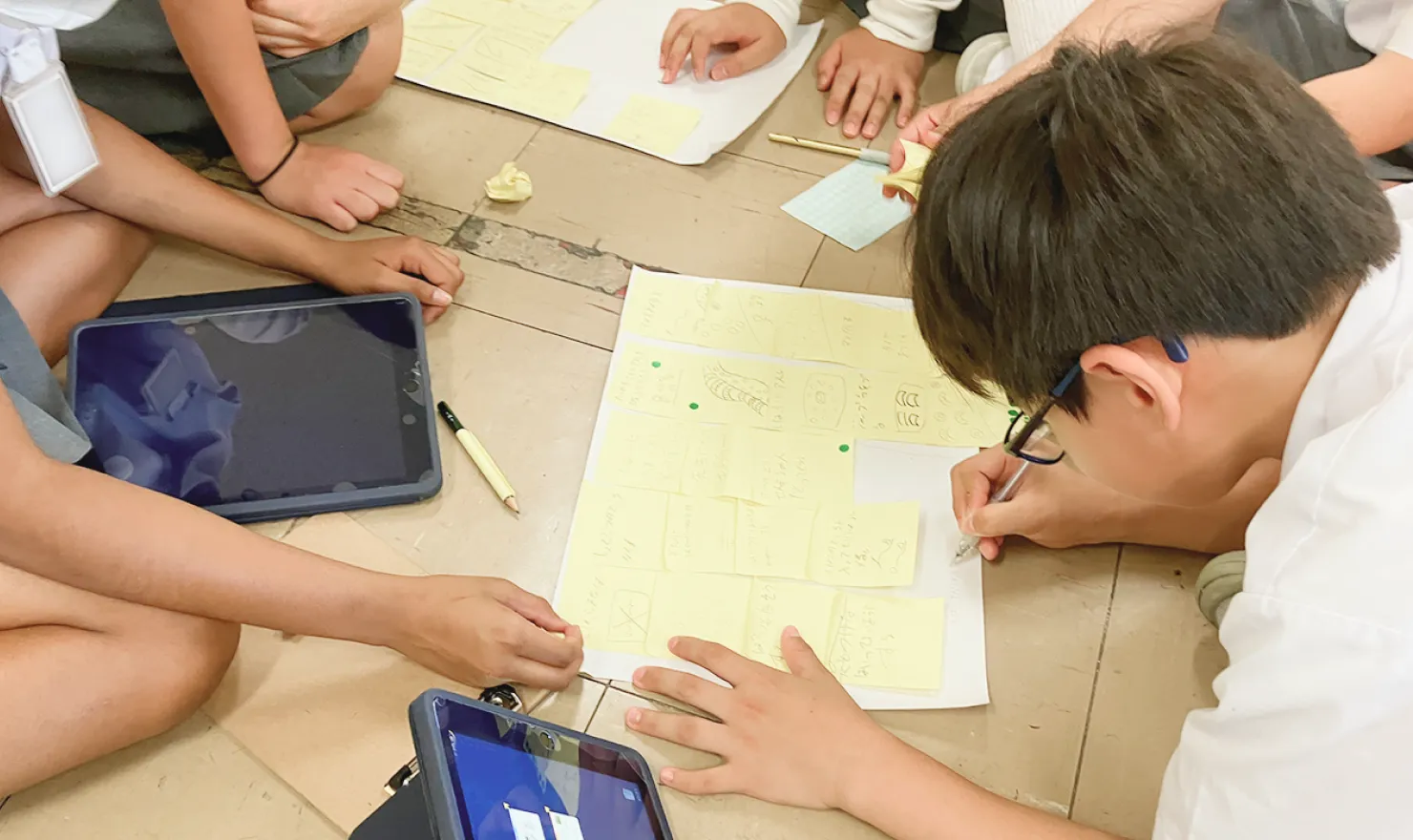 付箋に書き込んだアイデアを囲んで、話し合う児童たち。