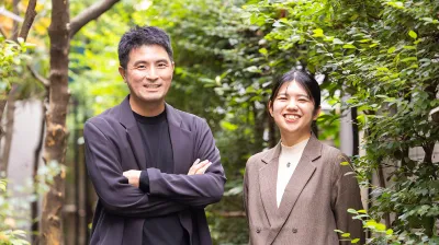 コンセントのコミュニケーションスペース「amu」を背景に、鈴木と大﨑が写るメインビジュアル。