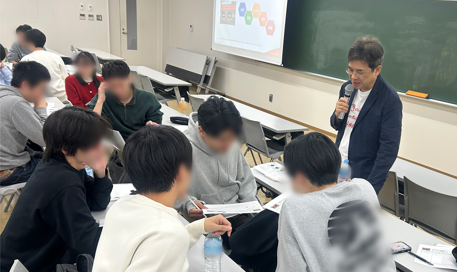 写真：中野が教室でマイクを持って講義している様子。