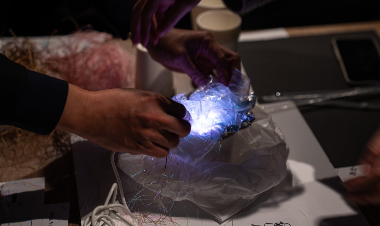 写真。アイデア試作品にあかりを灯す様子。ビニールの中に青系の色に灯したIoT試作機をいれることで、青白い光が乱反射して見える。