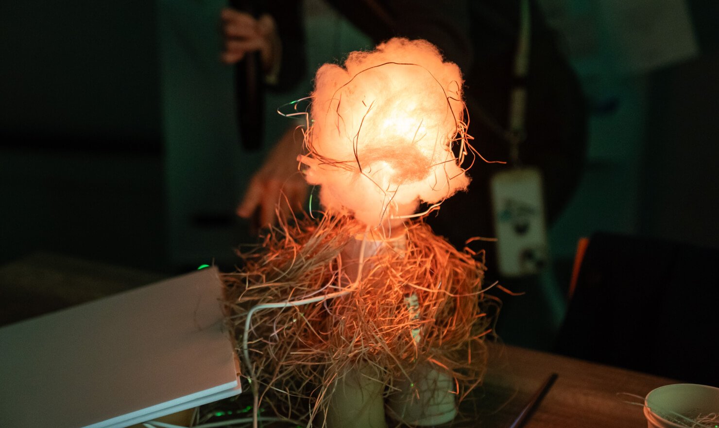 写真。アイデア試作品のひとつ。綿の中に赤系の色に灯したIoT試作機をいれることで、暖色の光が淡く光って見える。