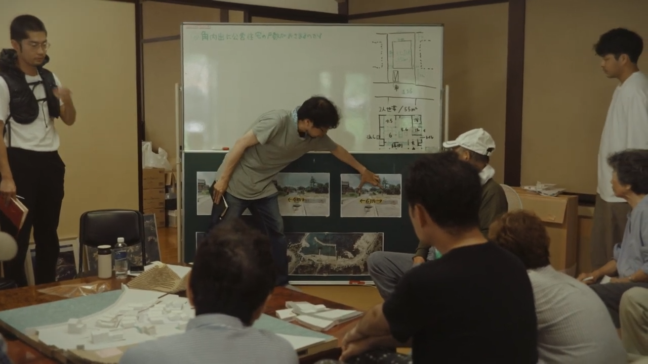 Season.2シーンカット。ホワイトボードを囲み、複数名が話し合っている様子。