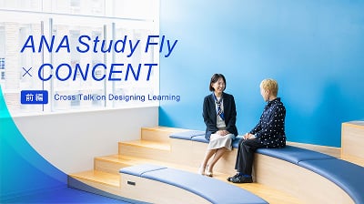 前編記事のメインビジュアル。青い壁のソファーのある会議スペースで二人が話し合う様子。