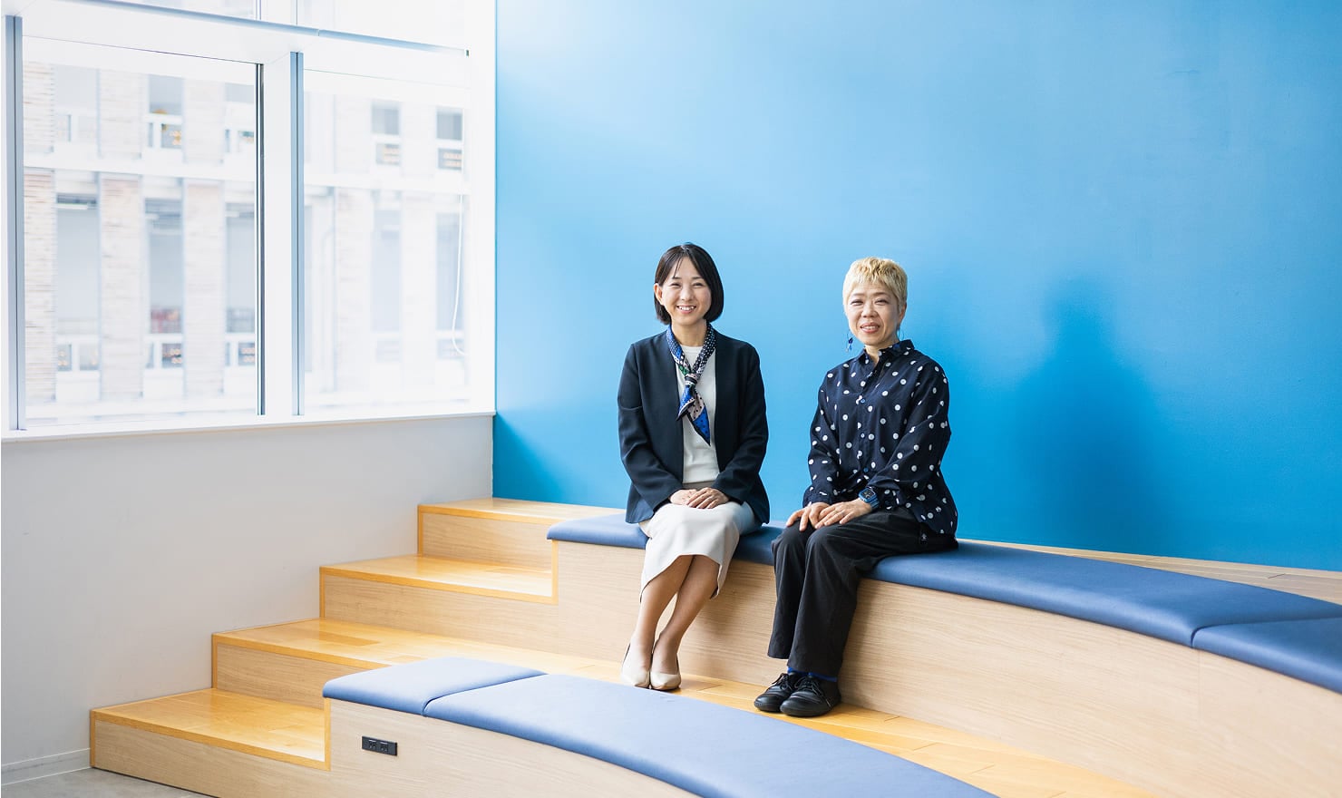 青い壁と広い空間のあるANAの会議室野中に座る、対談後の二人の様子